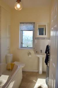 a bathroom with a sink and a toilet and a window at Cartref, 1860s family home. in Bridgend