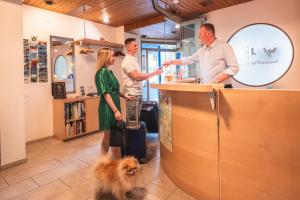 tres personas de pie en un mostrador en una tienda con un perro en Hotel Seehof Superior, en Walenstadt