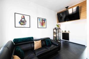 sala de estar con sofá de cuero negro y TV de pantalla plana en Apartment Design 5 Stelle, en Novara
