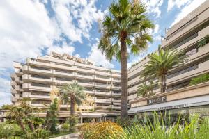 un gran edificio con palmeras delante en Agence AICI - Appartements Gray d'Albion, en Cannes