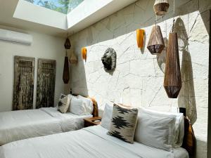 a bedroom with two beds and a stone wall at Naats Amigos Tulum in Tulum