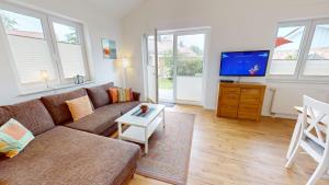 a living room with a couch and a tv at Feriendorf Südstrand Haus 35 in Pelzerhaken