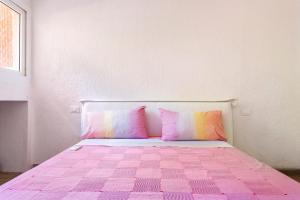 ein Schlafzimmer mit einem rosa Bett mit rosa Kissen in der Unterkunft Punta ala Fronte Mare in Punta Ala