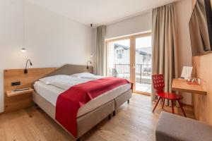 Habitación de hotel con cama, escritorio y ventana en Aparthotel Ursprung en Schladming