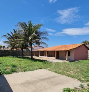a house with a palm tree next to a field at Casa Brisas in Luis Correia