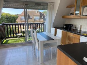 cocina con mesa y sillas y balcón en Picsine, Tennis résidence sévigné 300m mer, en Deauville