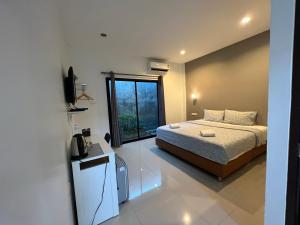 ein Schlafzimmer mit einem Bett und einem großen Fenster in der Unterkunft ซีมอน เกสเฮ้าส์ in Phetchaburi