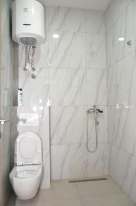 uma casa de banho branca com um chuveiro e um WC. em Apartmani Herceg em Gacko