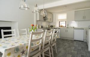 Una cocina y un comedor con mesa y sillas. en The Portpatrick Pad - A cosy 3 bed cottage, w. sea views & garden office, en Portpatrick