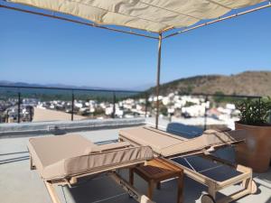 Duas espreguiçadeiras e um guarda-sol no telhado em Pyrgi Cretan Living & Spa em Pírgos