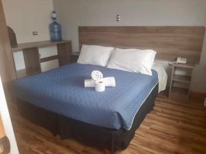 Una cama con un edredón azul y dos velas. en Hotel Amaru Express, en Arica