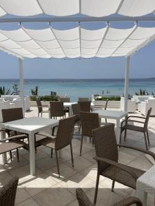 un patio con tavoli, sedie e vista sull'oceano di Hotel da Cesare Maluentu a Putzu Idu