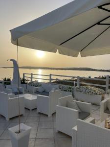 patio bianco con sedie bianche e ombrellone di Hotel da Cesare Maluentu a Putzu Idu