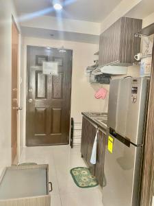 a small kitchen with a refrigerator and a door at Nice location in the persimmon condo in Cebu City