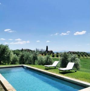 a swimming pool with two white chairs next to it at PodereVicoBasso Siena in Siena