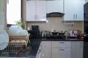 a kitchen with white cabinets and a black counter top at Serviced Apartment near Medanta by BedChambers in Gurgaon