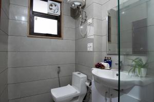 baño con aseo y lavabo y ventana en Serviced Apartment near Medanta by BedChambers en Gurgaon
