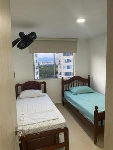 two beds in a room with a window at Estrene Lindo apartamento en Ricaurte cundinamarca con Club House in Ricaurte