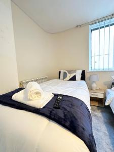 a bedroom with a large bed with white sheets and a window at City Stay in Colchester