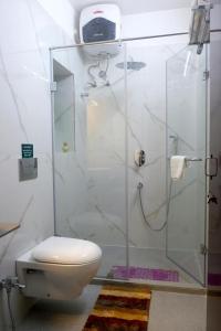 a bathroom with a toilet and a glass shower at Olys Apartment Gariahat in Kolkata