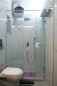 a bathroom with a glass shower with a toilet at Olys Apartment Gariahat in Kolkata