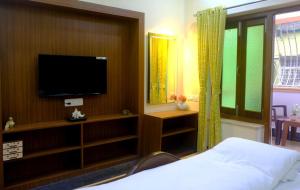 a bedroom with a flat screen tv and a bed at Olys Apartment Gariahat in Kolkata