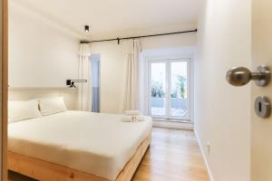 a white bedroom with a bed and a window at Sao Bento Classic by Homing in Lisbon