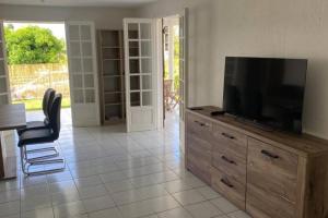 聖羅斯的住宿－Bas de villa Agréable - Ste-Rose，客厅配有木梳妆台上的电视
