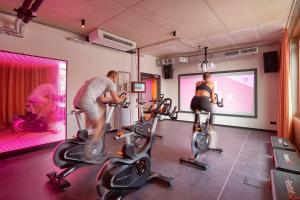 a man and woman riding on exercise bikes in a gym at Basecamp Hotel Dortmund in Dortmund