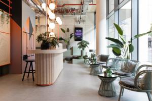 a lobby with tables and chairs and plants at Basecamp Hotel Dortmund in Dortmund