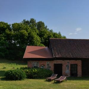 una casa de ladrillo con dos bancos delante en Camp Warmia, en Stare Kawkowo