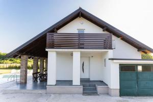 mały biały dom z zielonym garażem w obiekcie Kuća za odmor Bosut w mieście Vinkovci