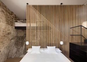 a bedroom with a white bed and a wooden wall at Cabana La Roca in La Roca