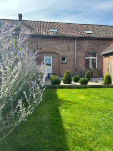 a brick house with a green lawn and flowers at The 75 renovated work or holiday home in Comines