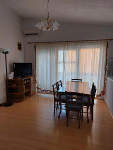 une salle à manger avec une table, des chaises et une télévision dans l'établissement Apartman Nardi, à Vir