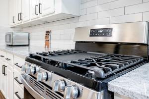 cocina con fogones y armarios blancos en Living in a Greenhouse - City Retreat - 3BR with 70 inches TV, en Farmers Branch