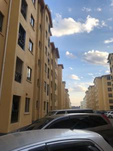 a parking lot with cars parked in front of buildings at PASWELL'S HOMES 3 Bedroom Apartment at Greatwall Gardens in Athi River