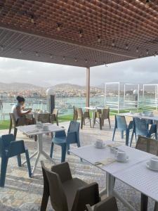 a woman sitting at a table in a restaurant with tables and chairs at Ouril Mindelo in Mindelo