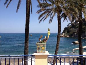 a statue on the beach with palm trees and the ocean at La casuzza di Tindaro in Catania