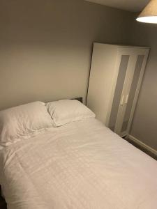 a bedroom with a bed with white sheets and a lamp at Cosy 1 Bed Home @Stevenage in Shephall