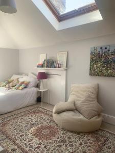 a bedroom with a bed and a chair and a skylight at Top Floor. Top Notch. Tranquil Treat. Stone's throw from Thames. in Maidenhead