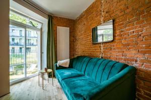 a green couch in a room with a brick wall at Cozy Studio 5 minut by Warsaw East in Warsaw