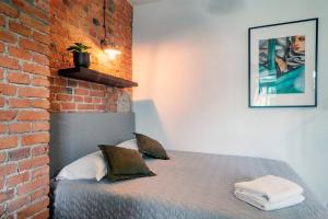 een bed in een kamer met een bakstenen muur bij Cozy Studio 5 minut by Warsaw East in Warschau