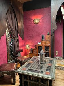 um quarto com uma mesa e cadeiras e paredes cor-de-rosa em Chambres d'hôtes - Le Nador em Meurchin