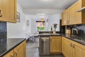 a kitchen with wooden cabinets and a stainless steel dishwasher at Silver Stag Properties, 4 BR in Ashby de la Zouch in Smisby