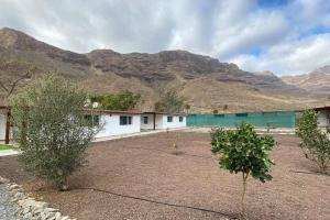 a building in a desert with mountains in the background at 2 Bedroom Country House Near Fataga & Maspalomas in Artedara