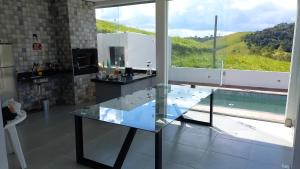 a glass table in a kitchen with a large window at Casa de campo in Natividade da Serra