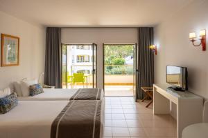 a hotel room with a bed and a television at Clube do Lago Hotel in Estoril
