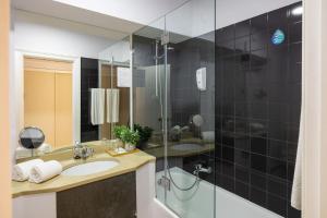 a bathroom with a sink and a glass shower at Clube do Lago Hotel in Estoril
