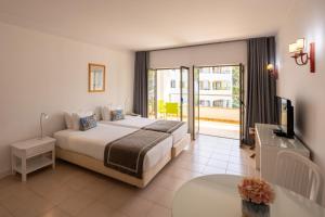 a bedroom with a bed and a television and a balcony at Clube do Lago Hotel in Estoril